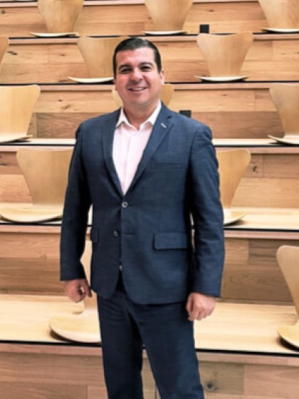 Manuel de la Garzaviejo Salinas, de pie con traje azul frente a unas gradas de madera.